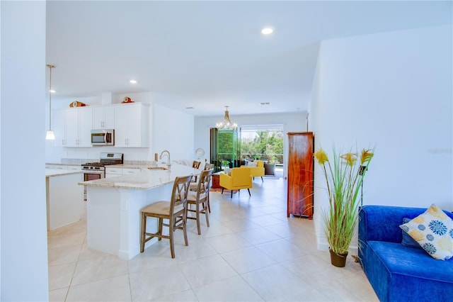 kitchen featuring sink, decorative light fixtures, white cabinetry, appliances with stainless steel finishes, and a breakfast bar