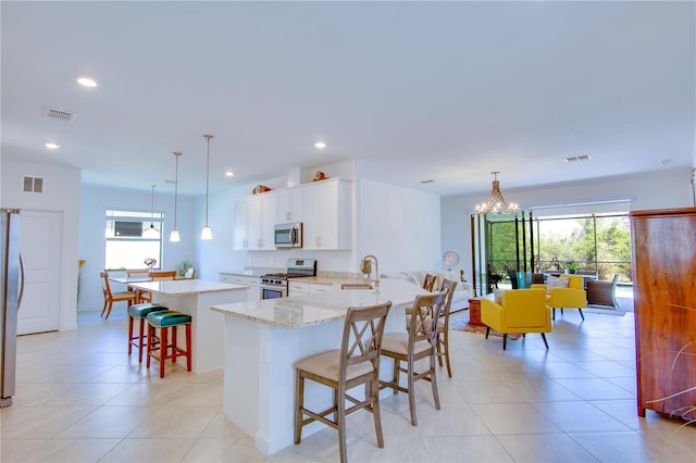 kitchen with white cabinetry, a breakfast bar, kitchen peninsula, pendant lighting, and stainless steel appliances