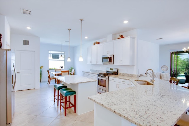 kitchen with pendant lighting, sink, kitchen peninsula, stainless steel appliances, and a breakfast bar area