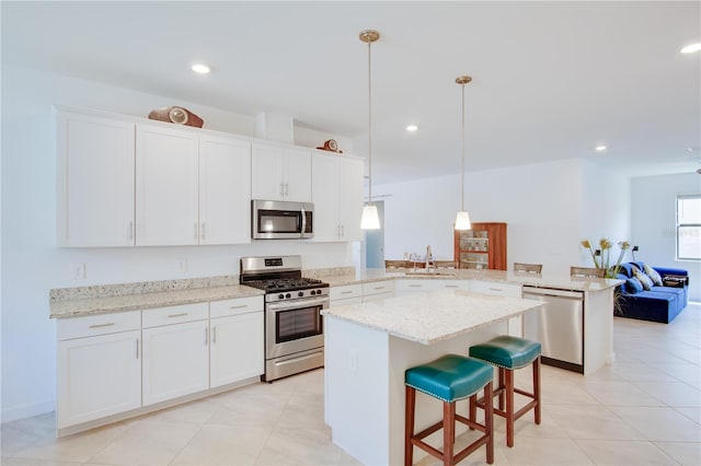 kitchen with pendant lighting, stainless steel appliances, kitchen peninsula, and white cabinets