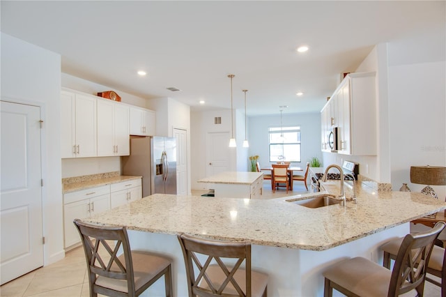 kitchen featuring hanging light fixtures, sink, a kitchen island, appliances with stainless steel finishes, and a breakfast bar