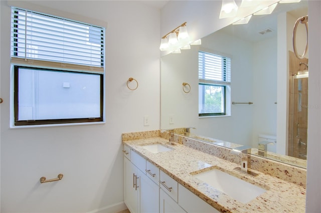 bathroom featuring vanity, a shower with shower door, and toilet