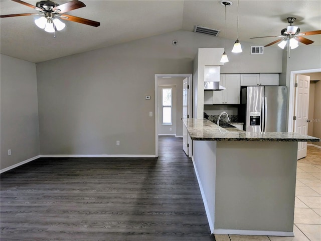 kitchen with stainless steel fridge with ice dispenser, a ceiling fan, lofted ceiling, light wood-style flooring, and dark stone countertops