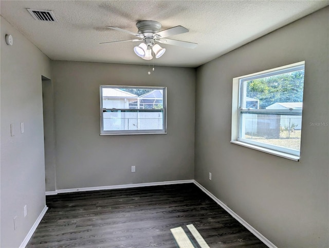 empty room with healthy amount of natural light, dark wood finished floors, a textured ceiling, and ceiling fan