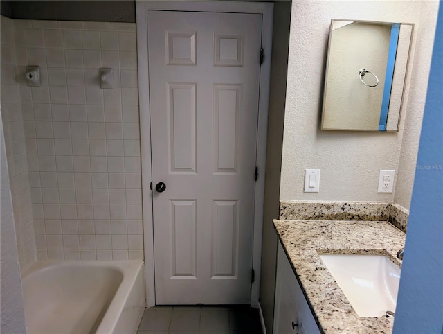 bathroom featuring tile patterned floors, vanity, a textured wall, and  shower combination