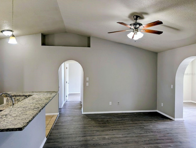 unfurnished living room featuring arched walkways, a ceiling fan, wood finished floors, a textured ceiling, and lofted ceiling
