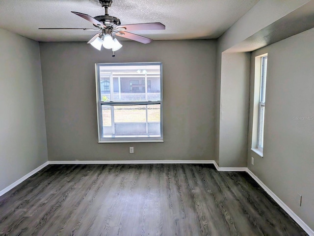 empty room featuring healthy amount of natural light, wood finished floors, a textured ceiling, a ceiling fan, and baseboards