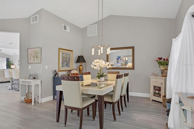 dining area featuring vaulted ceiling and light wood-type flooring