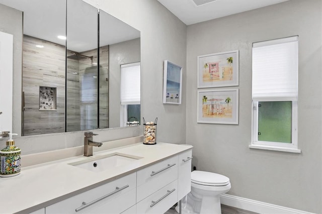 bathroom featuring tiled shower, vanity, and toilet