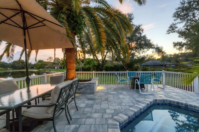 patio terrace at dusk featuring a water view