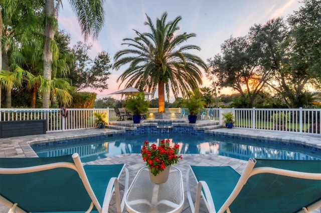 pool at dusk with a patio area