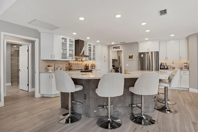 kitchen featuring a kitchen breakfast bar, white cabinetry, a center island, and stainless steel refrigerator