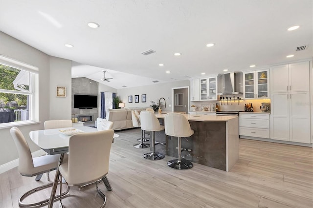 dining area with lofted ceiling, a large fireplace, and light hardwood / wood-style flooring