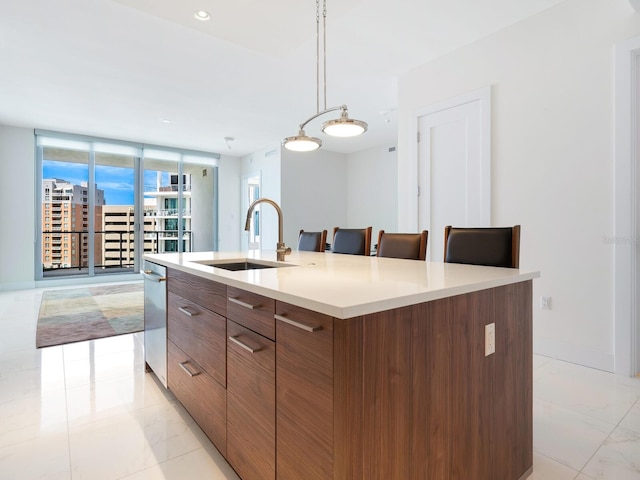 kitchen featuring a large island with sink, sink, hanging light fixtures, and a breakfast bar