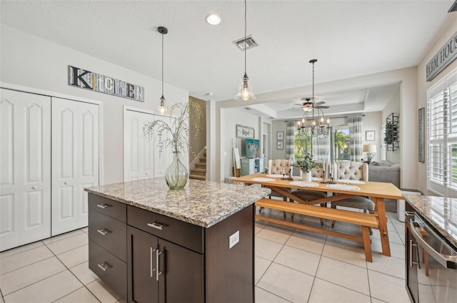 kitchen with dark brown cabinets, pendant lighting, light tile patterned floors, light stone countertops, and ceiling fan