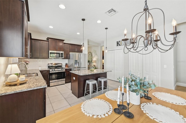 kitchen with light stone countertops, stainless steel appliances, a kitchen island, and sink