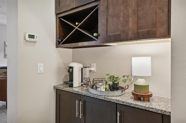 bar with dark brown cabinetry and light stone counters