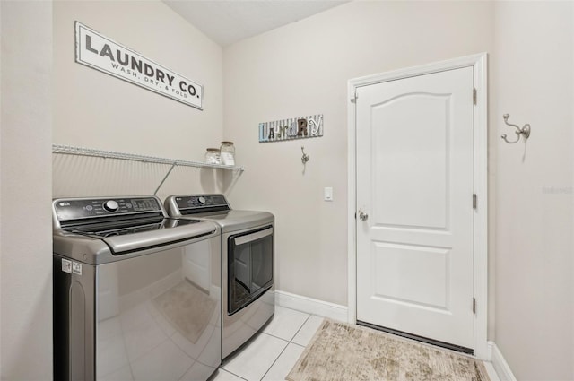 clothes washing area featuring light tile patterned floors and washer and dryer