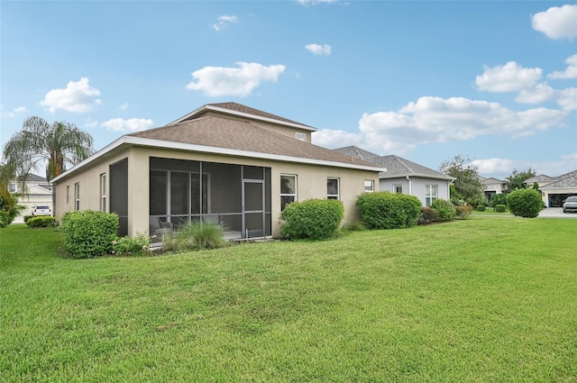 rear view of house with a sunroom and a lawn