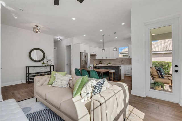 living room with light hardwood / wood-style flooring, ceiling fan, and sink