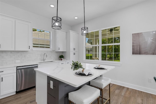 kitchen with pendant lighting, sink, white cabinets, and stainless steel dishwasher