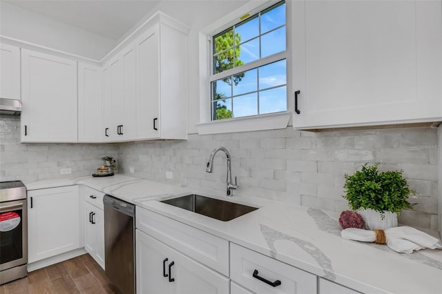 kitchen featuring dark hardwood / wood-style flooring, light stone counters, stainless steel appliances, sink, and white cabinetry