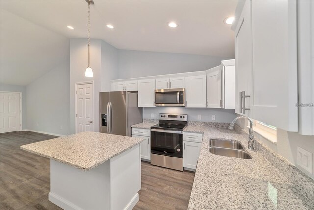 kitchen with hanging light fixtures, white cabinetry, stainless steel appliances, wood-type flooring, and sink