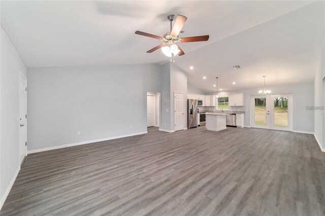 unfurnished living room with ceiling fan with notable chandelier, vaulted ceiling, and dark hardwood / wood-style floors