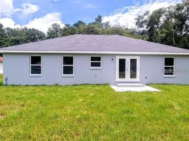 rear view of property featuring a lawn and french doors