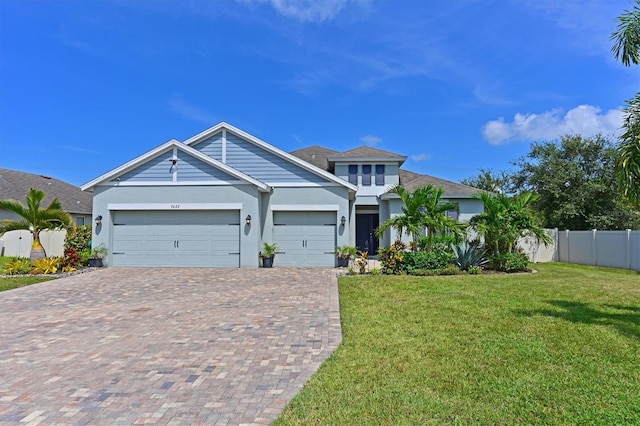 craftsman house with a garage, a front lawn, decorative driveway, and fence