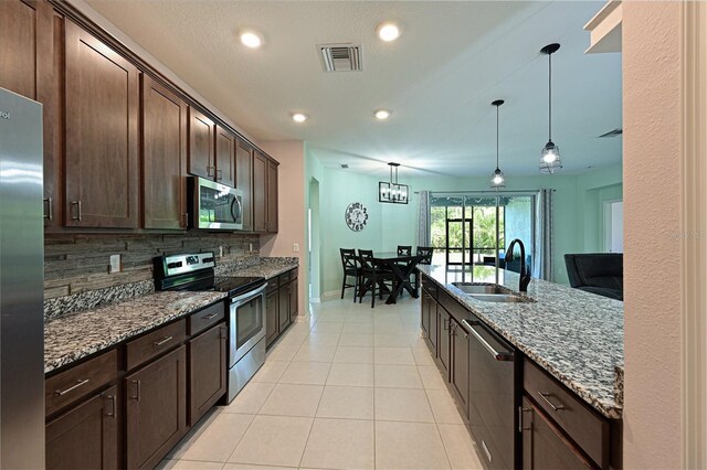 kitchen featuring sink, backsplash, stone counters, decorative light fixtures, and stainless steel appliances