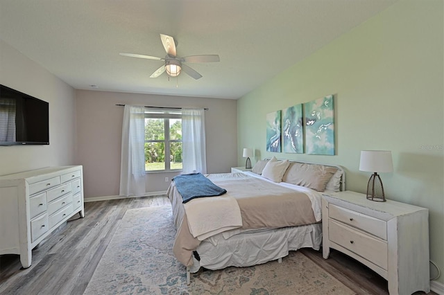 bedroom with wood finished floors, a ceiling fan, and baseboards