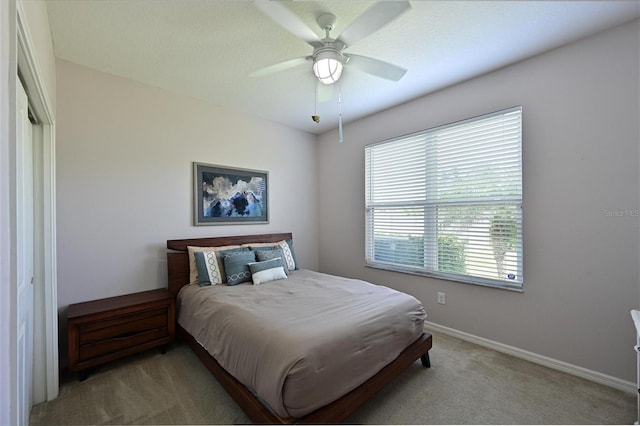 bedroom with ceiling fan, baseboards, and light carpet