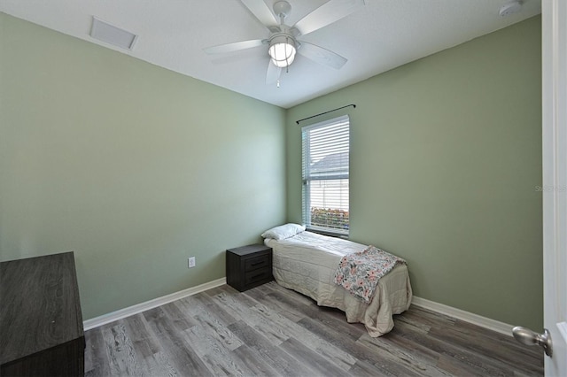 bedroom with baseboards, wood finished floors, visible vents, and a ceiling fan