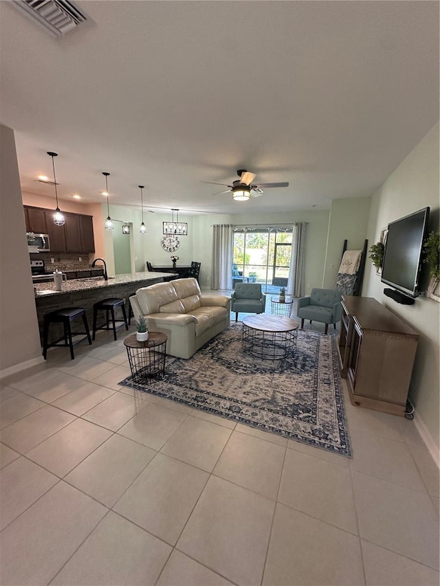 living room featuring sink, ceiling fan, and light tile patterned floors