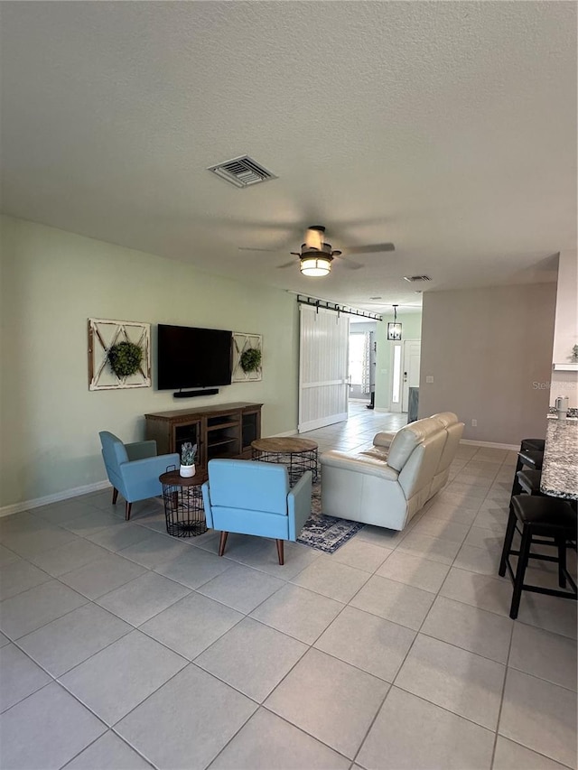 living room with a textured ceiling, ceiling fan, and light tile patterned floors