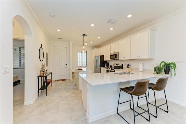 kitchen with sink, white cabinets, kitchen peninsula, hanging light fixtures, and appliances with stainless steel finishes