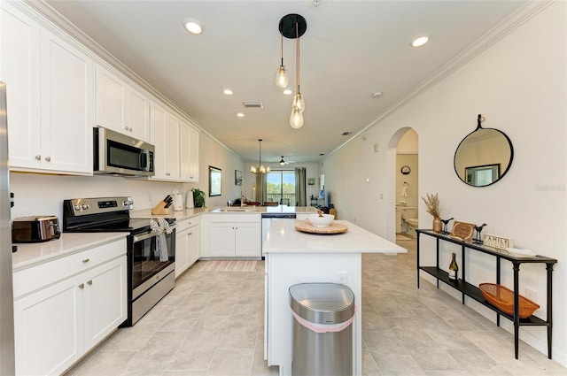 kitchen featuring appliances with stainless steel finishes, white cabinets, kitchen peninsula, crown molding, and decorative light fixtures