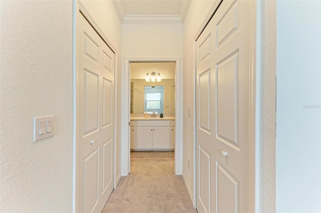 hall with light colored carpet, crown molding, and sink