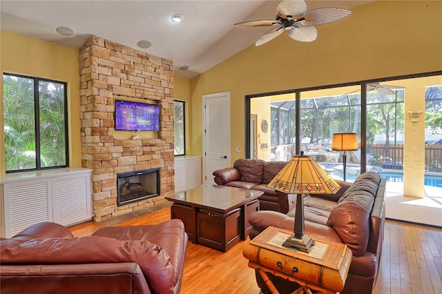 living room with light wood-type flooring, vaulted ceiling, ceiling fan, and plenty of natural light