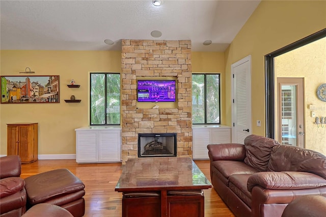 living room featuring light hardwood / wood-style flooring, lofted ceiling, a healthy amount of sunlight, and a fireplace