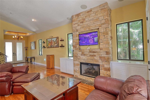 living room with a wealth of natural light, lofted ceiling, a fireplace, and light wood-type flooring