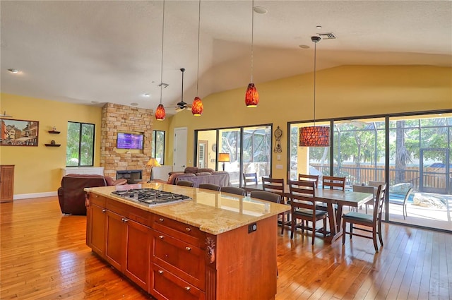 kitchen featuring pendant lighting, light stone countertops, a fireplace, and stainless steel gas cooktop