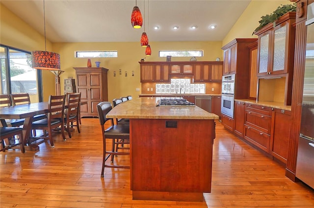 kitchen with pendant lighting, vaulted ceiling, light hardwood / wood-style flooring, and a kitchen island