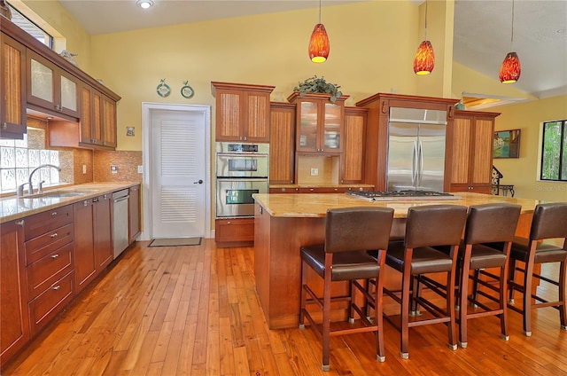 kitchen featuring stainless steel appliances, light wood-type flooring, sink, and a healthy amount of sunlight