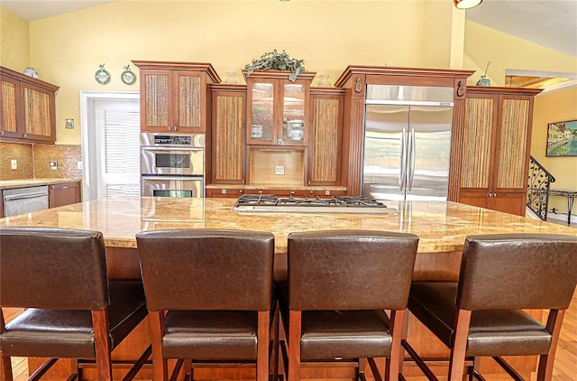 kitchen featuring a breakfast bar area, lofted ceiling, stainless steel appliances, backsplash, and hardwood / wood-style floors