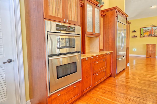 kitchen featuring light stone countertops, stainless steel appliances, and light hardwood / wood-style flooring