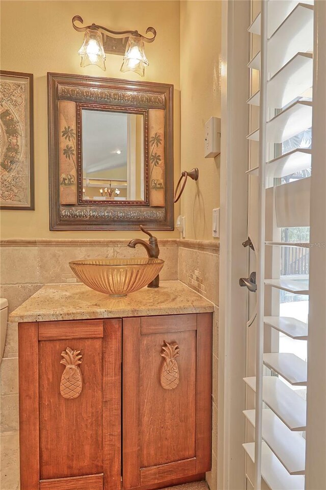 bathroom with tile walls, vanity, and toilet