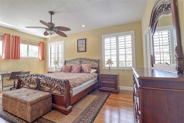 bedroom with multiple windows, a textured ceiling, light wood-type flooring, and ceiling fan