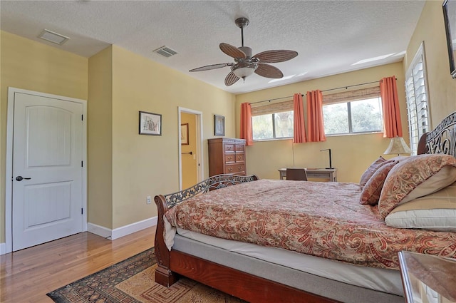 bedroom with light wood-type flooring, a textured ceiling, and ceiling fan